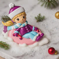 Load image into Gallery viewer, Christmas ornament of a girl on a sled with winter accessories.