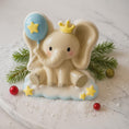 Load image into Gallery viewer, Decorative elephant figurine with a blue balloon and yellow stars on a white surface with greenery.