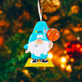 Load image into Gallery viewer, Personalized basketball gnome Christmas ornament featuring a cute blue gnome character holding a basketball, customizable name area on the hat and customizable year area on the base, glossy finish with raised 3D front details and flat 2D back, white hanging ribbon, displayed on a snowy holiday background with pine branches and festive decorations.
