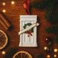 Load image into Gallery viewer, Decorative Christmas ornament resembling a fireplace with a wreath and ribbon on a wooden surface with festive elements.