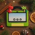 Load image into Gallery viewer, tablet ornament with dinosaur and tropical scene on a wooden surface with Christmas decorations.