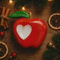 Load image into Gallery viewer, Red ceramic apple with a white center on a wooden surface with cinnamon sticks and oranges.