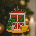 Load image into Gallery viewer, Decorative Christmas ornament shaped like a barn with wreaths, a tree, and a lantern on a blurred Christmas tree background.