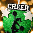 Load image into Gallery viewer, Personalized cheerleading Christmas ornament featuring a bright green glitter background with a cheer silhouette holding pom poms, bold CHEER title at the top, customizable name area on the lower banner, customizable year displayed on a star detail, and additional personalization space for school name or initials, glossy finish with raised 3D front elements and flat 2D back, white hanging ribbon, photographed on a snowy sports field themed holiday background with festive ornaments and winter greenery.