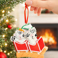 Load image into Gallery viewer, Christmas ornament of two puppies in a red box held by a hand with a festive background.
