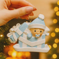 Load image into Gallery viewer, Personalized Baby Boy First Christmas Ornament featuring an adorable baby popping out of a blue gift box with a matching hat and pacifier. The name is displayed on the hat while the year is placed on the ribbon detail, with Baby’s 1st Christmas written along the base. Soft blue and white tones, raised 3D elements, and sweet holiday details make this a charming keepsake. Perfect for newborn boys, baby showers, and celebrating a baby’s very first Christmas season.