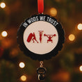 Load image into Gallery viewer, Personalized weightlifting and fitness Christmas ornament featuring a raised 3D front with bold circular design and red strength icons including boxing, gymnastics rings, and weightlifting. The ornament has a textured black outer rim and a flat 2D back for easy hanging. Includes a hanging kettlebell charm for added depth and movement. Hand-added personalization allows a name and year or family name. Photographed on a festive Christmas tree background with warm holiday lights.
