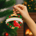 Load image into Gallery viewer, Personalized cardinal wreath ornament featuring a vibrant red cardinal bird surrounded by green holly leaves and red berries. Designed with a smooth glossy finish and a raised 3D front with a flat back for easy hanging. Includes free handwritten personalization with one name and year displayed on the banner at the top. Styled in a warm festive holiday setting with soft Christmas lights candy details and seasonal decor. A meaningful Christmas tree ornament symbolizing remembrance love and connection perfect