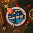Load image into Gallery viewer, Decorative ornament with telescope, planets, and stars on a wooden surface with Christmas decorations.
