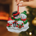 Load image into Gallery viewer, Decorative Christmas ornament of snowmen with a blurred festive background