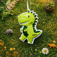 Load image into Gallery viewer, Personalized dinosaur Christmas ornament with a raised 3D front featuring a cute green dinosaur design and glossy detailed texture. The ornament has a flat 2D back for easy hanging and durability. Bright green color, playful smile, and sculpted spikes create a fun and eye catching look. Hand personalized with name and year. Perfect kids Christmas ornament, dinosaur themed holiday decor, and personalized keepsake gift.