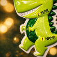 Load image into Gallery viewer, Personalized dinosaur Christmas ornament with a raised 3D front featuring a cute green dinosaur design and glossy detailed texture. The ornament has a flat 2D back for easy hanging and durability. Bright green color, playful smile, and sculpted spikes create a fun and eye catching look. Hand personalized with name and year. Perfect kids Christmas ornament, dinosaur themed holiday decor, and personalized keepsake gift.