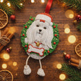 Load image into Gallery viewer, Decorative Christmas ornament of a dog with a Santa hat on a wooden surface with festive decorations.