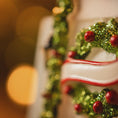 Load image into Gallery viewer, Decorative cake with green glittery wreath and red berries on a blurred festive background