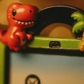 Load image into Gallery viewer, Red dinosaur toy figure on a green and black toy car