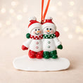 Load image into Gallery viewer, Two snowman ornaments on a white base with a blurred light background