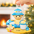 Load image into Gallery viewer, Personalized Beach Baby Christmas Ornament featuring a cheerful toddler sitting on the sand with a beach hat, float, bucket, and shovel. This detailed 3D front design includes raised elements, bright summer colors, and textured sand base for added depth. The name is placed on the hat and the year on the sandy base. A perfect keepsake for baby’s first beach trip or summer memory, ideal for Christmas tree decor or a thoughtful holiday gift for new parents.