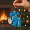 Load image into Gallery viewer, Personalized nurse ornament featuring blue medical scrubs with stethoscope and clipboard design. Custom name and year displayed on the ornament. Smooth resin finish with mostly 2D structure and raised 3D front details. Ideal Christmas ornament for nurses healthcare workers and medical professionals celebrating the holiday season.