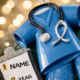 Load image into Gallery viewer, Personalized nurse ornament featuring blue medical scrubs with stethoscope and clipboard design. Custom name and year displayed on the ornament. Smooth resin finish with mostly 2D structure and raised 3D front details. Ideal Christmas ornament for nurses healthcare workers and medical professionals celebrating the holiday season.