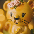 Load image into Gallery viewer, Personalized baby lion Christmas ornament featuring a sweet yellow lion cub wearing a floral crown and holding a small leaf. The bottom banner can be customized with name and year, creating a unique keepsake for a newborn or toddler. Designed in warm yellow and soft pastel tones, this resin baby Christmas ornament is perfect for celebrating Baby’s First Christmas or adding a personalized jungle themed touch to your holiday tree.
