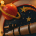 Load image into Gallery viewer, Close-up of a toy figure with a red ball and star design on a blurred background