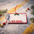 Load image into Gallery viewer, License plate with 'NEW DRIVER' text surrounded by Christmas decorations on a road.