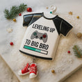 Load image into Gallery viewer, Cookie shaped like a t-shirt ornament with 'Leveling Up to Big Bro' text, red sneakers charm, on a decorative surface.