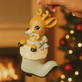 Load image into Gallery viewer, A glossy resin baby deer ornament features a cute fawn character sitting inside a soft pastel blue winter boot, holding a striped candy cane, with gentle antler details, smooth painted cartoon style finish, soft holiday lighting and blurred festive background, handwritten personalization showing the baby name on the boot and the year or Baby’s First Christmas text below, designed as a mostly 2D ornament with raised 3D details on the front only.