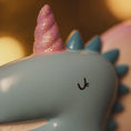 Load image into Gallery viewer, Unicorn-shaped object with a pink horn and blue spikes, blurred background