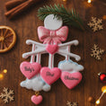 Load image into Gallery viewer, Personalized Baby Girl First Christmas Ornament featuring a dimensional 3D front design with pink glitter bow, heart charms, and hanging cloud detail. The baby’s name is added on the top circle and the year on the cloud, creating a meaningful keepsake. Soft pink tones, layered hearts reading Baby’s First Christmas, and festive holiday accents make it perfect for newborn girl gifts, baby shower presents, and treasured Christmas tree memories.