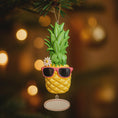 Load image into Gallery viewer, Pineapple ornament with sunglasses on a blurred Christmas tree background