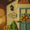 Load image into Gallery viewer, Decorative model of a house with 'SHE SHED' sign and garden-themed door.