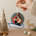 Load image into Gallery viewer, Decorative Christmas ornament of a boxer in a boxing ring held by a hand with festive background.