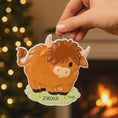 Load image into Gallery viewer, Adorable Highland cow themed Christmas ornament featuring a fluffy brown cow design with soft rounded details and a warm countryside feel. Styled in a natural green meadow setting, this ornament is designed to be personalized and brings a cozy farm inspired charm to holiday tree decor.