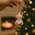 Load image into Gallery viewer, Personalized Pink Teddy Bear Christmas Ornament featuring a sweet baby bear wearing a cozy winter hat and holding a heart that can be customized with a name and year or Babyâs 1st Christmas. This adorable baby girl ornament is designed in soft pink tones, perfect for celebrating a newbornâs first holiday season. A heartwarming keepsake gift for new parents, baby showers, or a special Christmas memory that will be treasured for years to come.