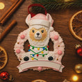 Load image into Gallery viewer, Personalized pink llama Christmas ornament featuring a cute white llama wrapped in colorful holiday lights, framed in a glittery wreath with pink accents. The top hat band can be customized with a name, while the bottom banner allows space for year or Babyâs 1st Christmas. Designed in soft pink and festive tones, this resin baby girl Christmas ornament makes a meaningful keepsake gift for celebrating a newbornâs first holiday season.