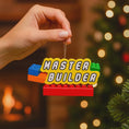 Load image into Gallery viewer, Personalized Master Builder Christmas ornament featuring a raised 3D front with colorful building block design and bold lettering. The ornament has a flat 2D back for easy hanging and durability. Bright primary colors and playful block details make it perfect for kids who love building toys. Personalization includes name and year, added by hand, making it a fun and meaningful holiday keepsake for children and young builders.