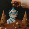 Load image into Gallery viewer, Decorative snowman ornament with blue accents held by a hand against a dark background.