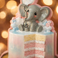 Load image into Gallery viewer, Personalized gender reveal Christmas ornament for baby girl featuring a pastel cake design with a cute elephant topper and its a gender message, soft pink and blue tones with layered cake details and glossy finish, styled as a sweet holiday keepsake for expecting parents, baby announcement and first Christmas memories, displayed on a warm wooden background with cozy Christmas lights, baby shoes and festive decor creating a joyful and heartwarming celebration scene