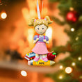 Load image into Gallery viewer, Decorative Christmas ornament of a girl with a pencil, books, and an apple on a blurred festive background.