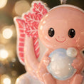 Load image into Gallery viewer, Cute pink character holding a snowball with a blurred festive background