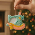 Load image into Gallery viewer, Personalized sewing machine ornament featuring a charming vintage style design with soft pastel colors and floral details. The ornament includes space for a name and year, making it a meaningful keepsake gift. Crafted from durable resin with a detailed 3D raised front and flat 2D back for smooth hanging. Includes free handwritten personalization. A perfect Christmas ornament gift for grandmothers sewing lovers quilters crafters and anyone who enjoys handmade traditions and creative hobbies.