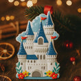 Load image into Gallery viewer, Personalized Princess Castle Christmas Ornament featuring a charming white fairytale castle with blue rooftops and red flags, surrounded by colorful floral details. Customizable with name at the base and year on the castle front, this magical princess castle ornament is perfect for celebrating a special little girl.
