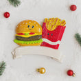 Load image into Gallery viewer, Decorative Christmas ornament shaped like a burger and fries on a snowy background with ornaments.
