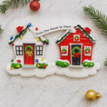 Load image into Gallery viewer, Christmas ornament shaped like two houses with wreaths and a banner on a snowy background.