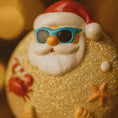 Load image into Gallery viewer, Santa Claus figurine with sunglasses on a beach-themed background