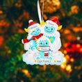 Load image into Gallery viewer, Christmas ornament with yeti family of three in winter clothing against a blurred Christmas tree background.