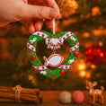 Load image into Gallery viewer, Personalized kitty Christmas ornament designed as a festive heart shaped wreath decorated with cat paw prints fish details and cozy holiday accents. The ornament includes a hanging heart tag that can be personalized with your cat’s name and year. Styled in a warm Christmas setting with soft snow texture and festive colors making it perfect for cat lovers holiday decor cat memorial keepsake and Christmas tree display.