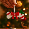 Load image into Gallery viewer, Festive pet themed Christmas ornament designed in a bone shape with a red holiday bow and paw detail. Featuring classic Christmas colors and a warm seasonal background, this ornament adds a joyful and loving touch to pet themed Christmas tree decor. Designed to be personalized with a name and year, making it a meaningful keepsake for pet owners and animal lovers.