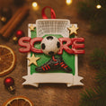 Load image into Gallery viewer, Soccer-themed Christmas ornament with 'SCORE' and soccer ball design on a wooden surface.